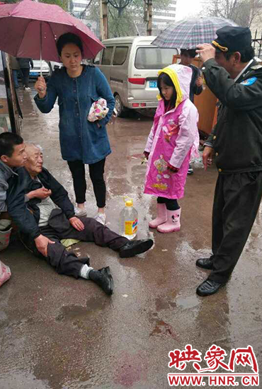 女孩為倒地老人撐傘。