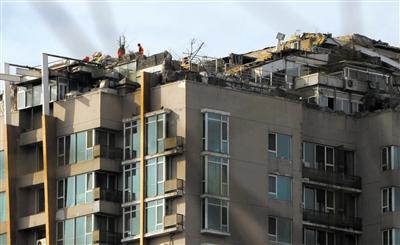 　　昨日，身穿橘黃色馬甲的工作人員在人濟山莊樓頂拆除違章建筑。新京報記者 吳江 攝