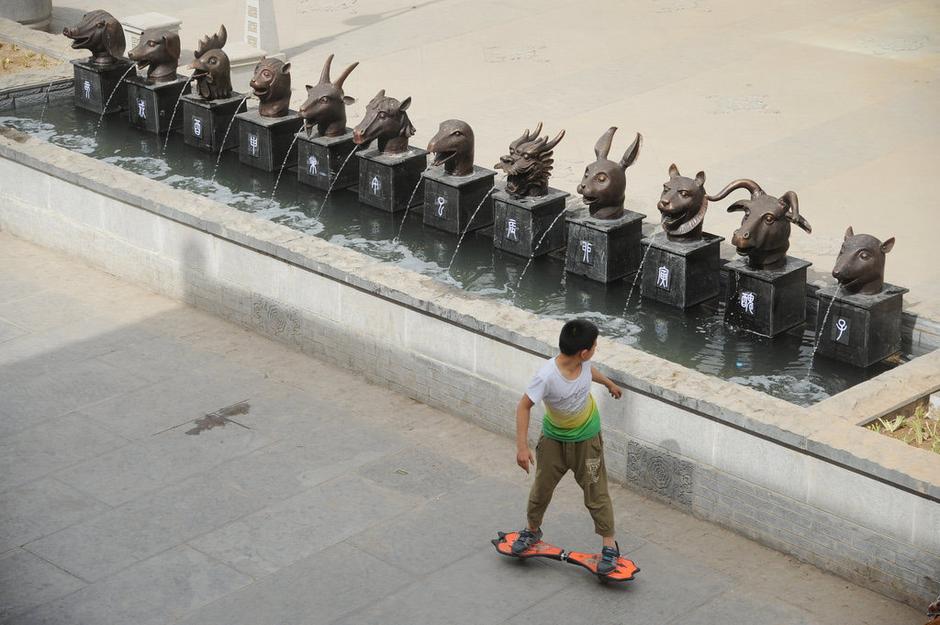 圖為一名市民從獸首旁經(jīng)過。