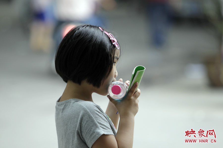 6月7日，鄭州回中考點(diǎn)，一名孩子拿著一瓶礦泉水，等待哥哥走出考場