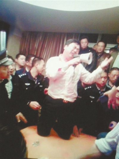 　4月19日，泰州市濱江工業(yè)園區(qū)管委會招待中心，一男子跪在酒桌上喊話求饒。李根 攝