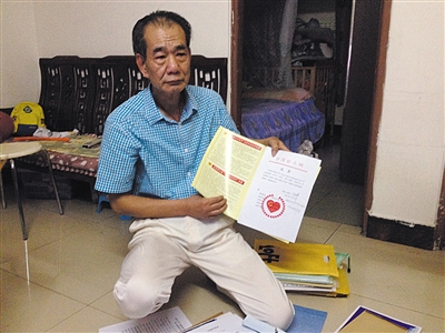 翻出一家網(wǎng)站贈予的“中國好人”證書，區(qū)少坤單膝跪在地上，“你看，我是中國好人啊。” 范春旭 攝