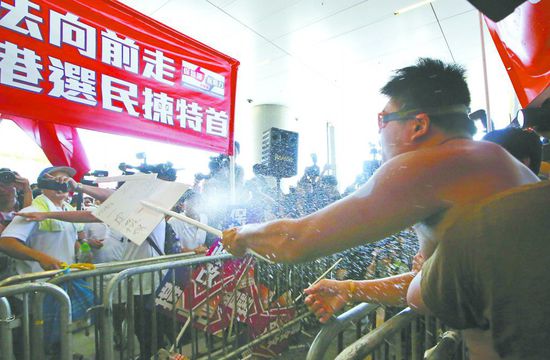 17日，在香港立法會(huì)外，一名反對(duì)政改的男子向支持派人群投擲標(biāo)牌。