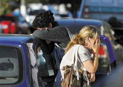 27日，遇難者親友在火災(zāi)現(xiàn)場(chǎng)旁哭泣。