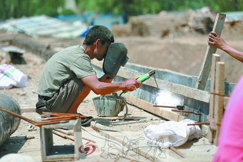　正午陽(yáng)光下，工地上的焊接工人還在認(rèn)真工作。