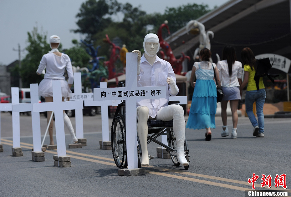 4月16日，重慶市洋人街上擺放著兩個(gè)受了傷的塑料人像“模特”，旁邊十字架上寫著向“中國(guó)式過馬路”說不