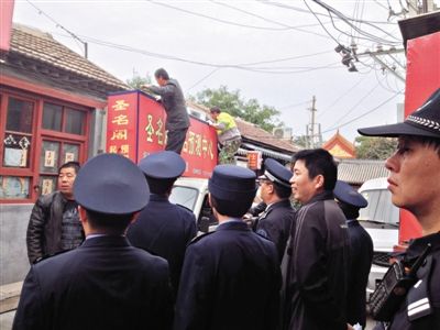 昨日下午,東城區(qū)工商、城管、公安等部門,對雍和宮附近的預(yù)測中心進行清理整頓,站在車頂?shù)膬擅と苏鸪患摇邦A(yù)測中心”的招牌。因雍和宮、白云觀等文化景點外聚集大量算命先生,被媒體稱為“算命一條街”。本版攝影/新京報記者 李寧 攝