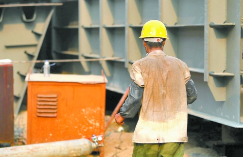 工地上，一建筑工人的衣服被汗水浸透。