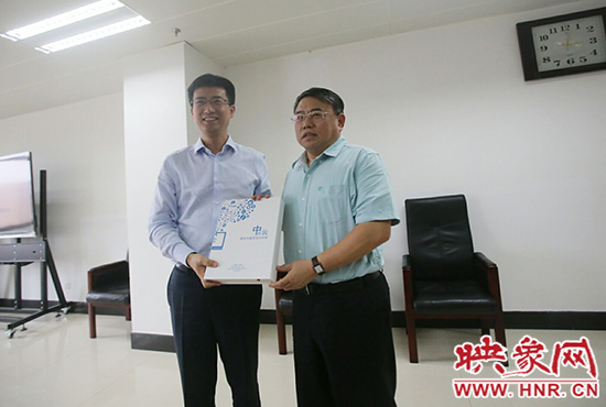 阿里云計算總裁胡曉明向河南省新聞出版廣電局局長朱夏炎遞交《中原云平臺交付手冊》。