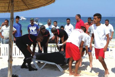 6月26日，在突尼斯蘇塞，救生員和醫(yī)務(wù)人員在發(fā)生襲擊事件的海灘運送一名死者的遺體。新華社發(fā)