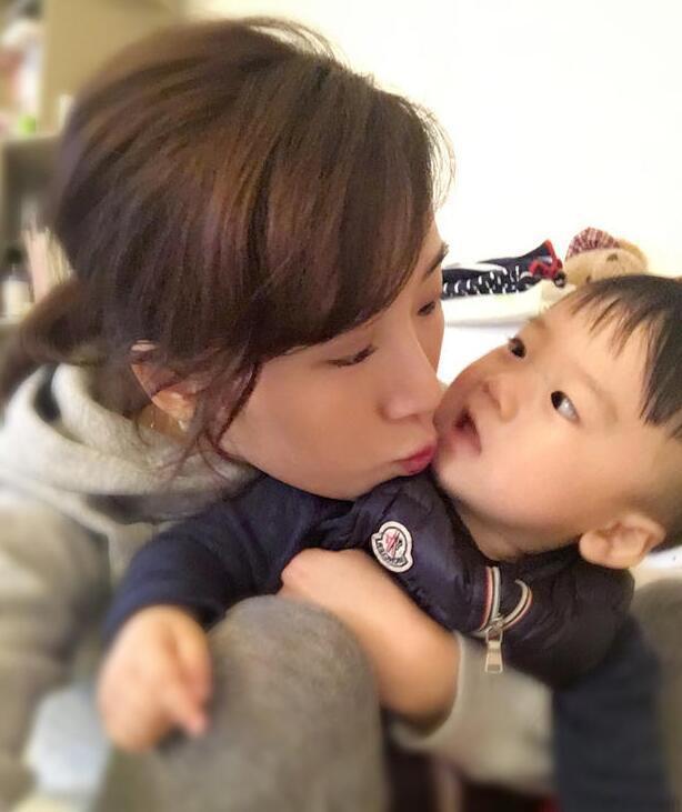 照片中李念狂吻兒子，小寶貝自顧自地玩著。