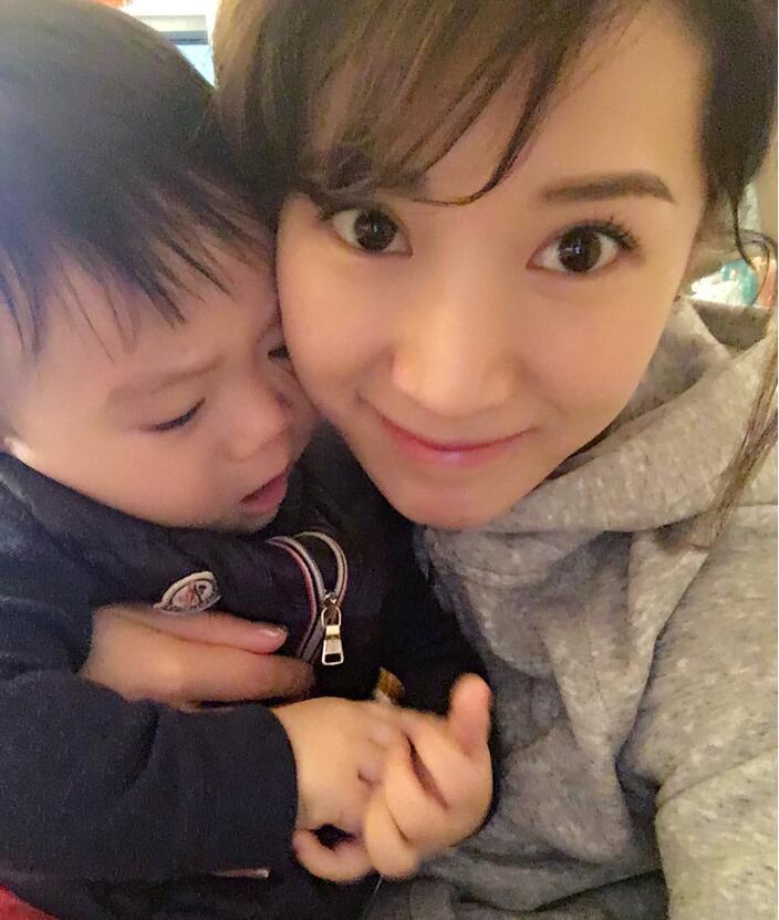 照片中李念狂吻兒子，小寶貝自顧自地玩著。