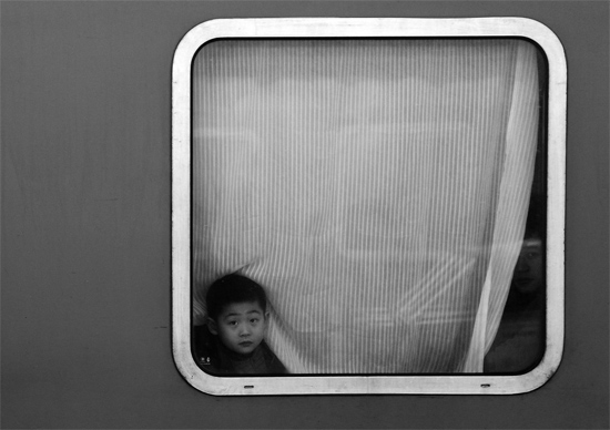 一個孩子把頭伸向窗外，他想再看送別的親人一眼