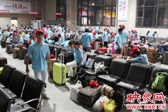 大學(xué)生志愿者在火車(chē)站候車(chē)室內(nèi)整裝待發(fā)。