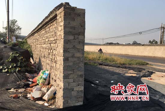 一墻之隔，一邊是道路，一邊是垃圾和荒草，市民質(zhì)疑其為遮羞墻。
