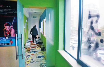 　健身會(huì)所地上一片狼藉，玻璃上噴著黑色“欠錢”二字。