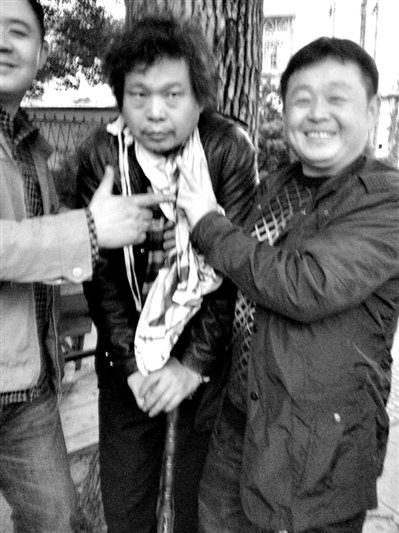 兩名接訪人員與患有癌癥的訪民段新德合影時，面帶笑容擺出勝利的手勢。