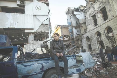 埃及曼蘇拉市警察局24日遭汽車炸彈襲擊，被疑是穆兄會的報復(fù)。圖為一名男子在被炸毀的警察局前。