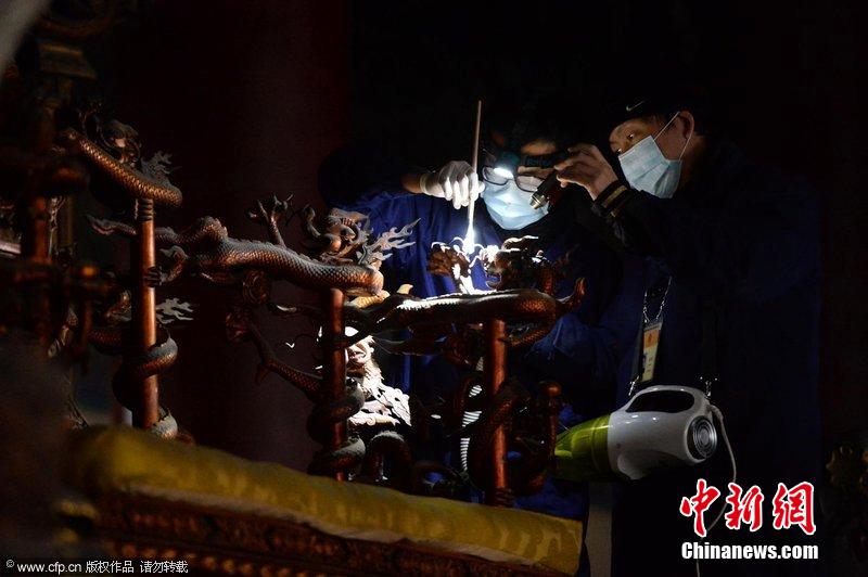 圖為工作人員使用軟毛刷和吸塵器對太和殿的金漆雕龍寶座除塵。