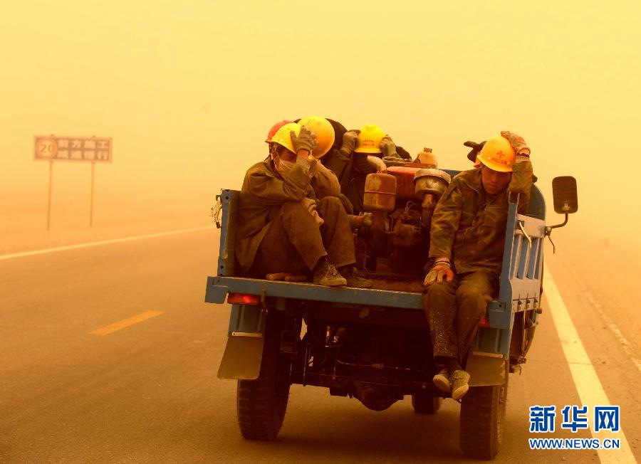 4月23日，一輛拉載公路施工人員的三輪車在沙塵暴中行駛在酒泉市瓜州縣城郊的公路上。