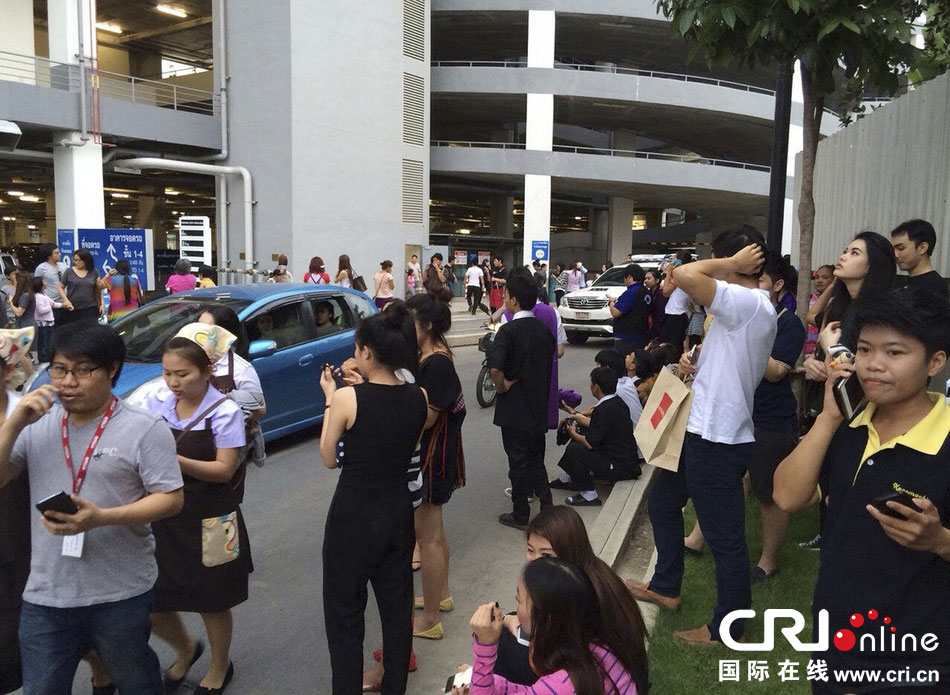 當(dāng)?shù)貢r(shí)間2014年5月5日，泰國清萊，工人們站在一棟大樓外避難。