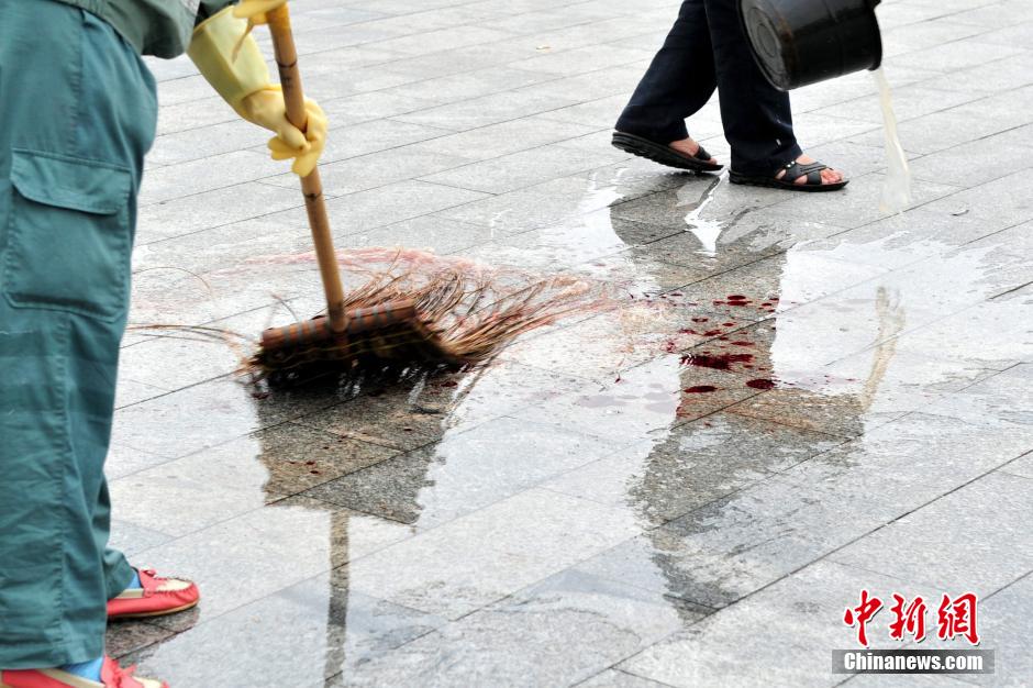 圖為環(huán)衛(wèi)工人在清理案發(fā)地點的血跡。