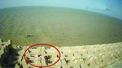 孫正龍游上岸，趴在海邊精疲力盡。