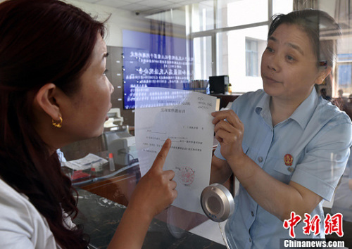 資料圖：2015年5月4日，河北石家莊市橋西區(qū)人民法院立案庭庭長齊燕正在為立案人辦理相關手續(xù)，完成整個過程只用了5分鐘。當日是立案登記制改革首個工作日，該院共立案36件，立案率達到90%。中新社發(fā) 翟羽佳 攝