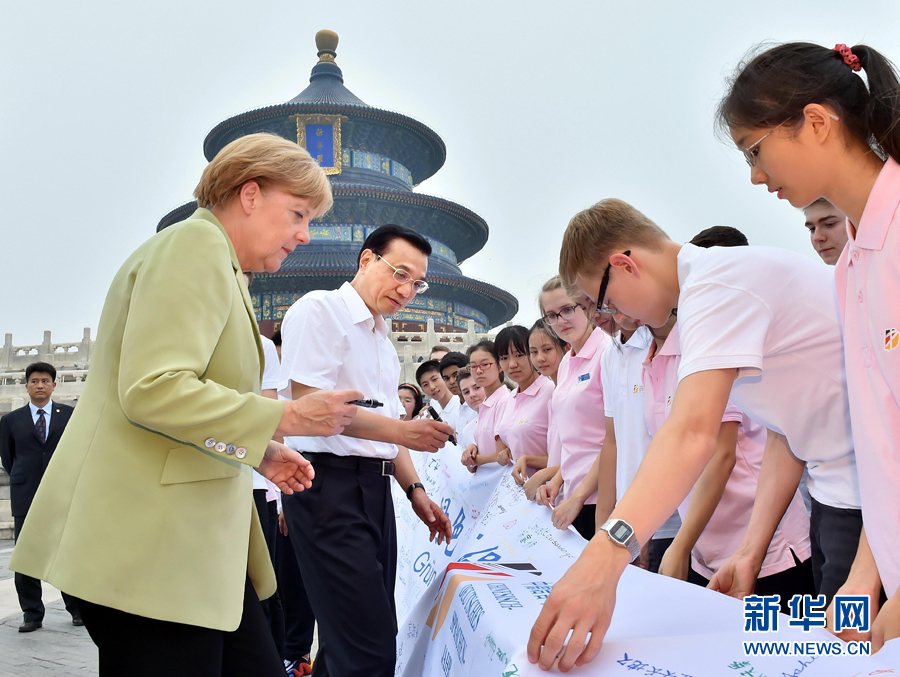 李克強(qiáng)同默克爾在紀(jì)念橫幅上簽名。