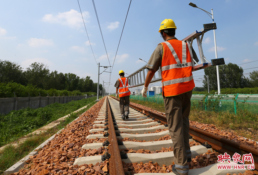 滾燙的鐵軌上，兩個(gè)扛著梯子的檢修員走向第四個(gè)檢修點(diǎn)
