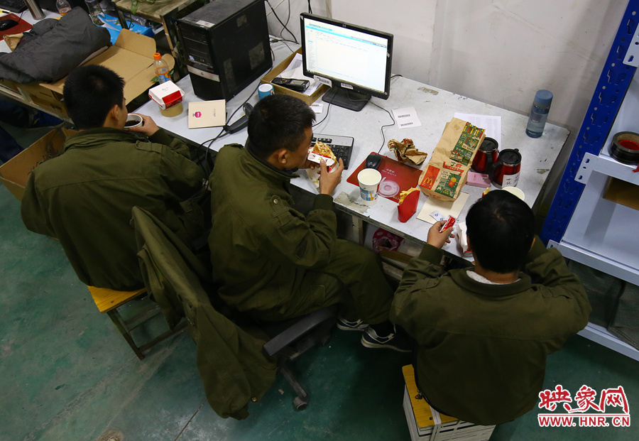 在工作臺前抓緊時(shí)間吃夜宵的員工們