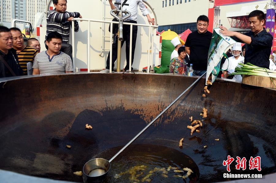 工作人員向大鍋內(nèi)加入油和姜等烹飪調(diào)料。 圖片來源：CFP視覺中國(guó)