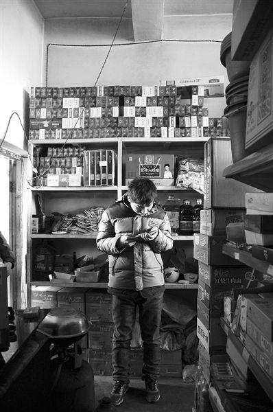 1月21日，周瑋在自家的超市里玩計(jì)算器。