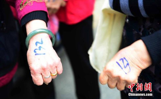 圖為10月28日，在江西九江市一家羊絨皮草服裝服飾博覽會現(xiàn)場，老人們正在頂著寒風排隊等待領取10元代金劵。