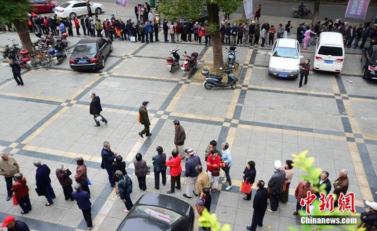 圖為10月28日，在江西九江市一家羊絨皮草服裝服飾博覽會現(xiàn)場，老人們正在頂著寒風排隊等待領取10元代金劵。