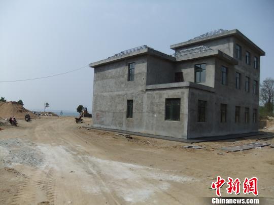 鴨河水庫庫區(qū)邊的新建別墅，一面墻上寫著“拆”，另一邊在加緊施工。吳揚　攝